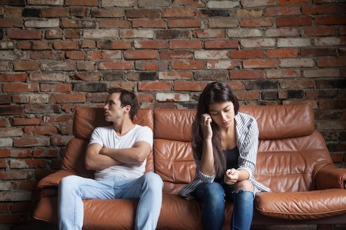 The popular book, a couple sits on a couch and both look frustrated with each other 